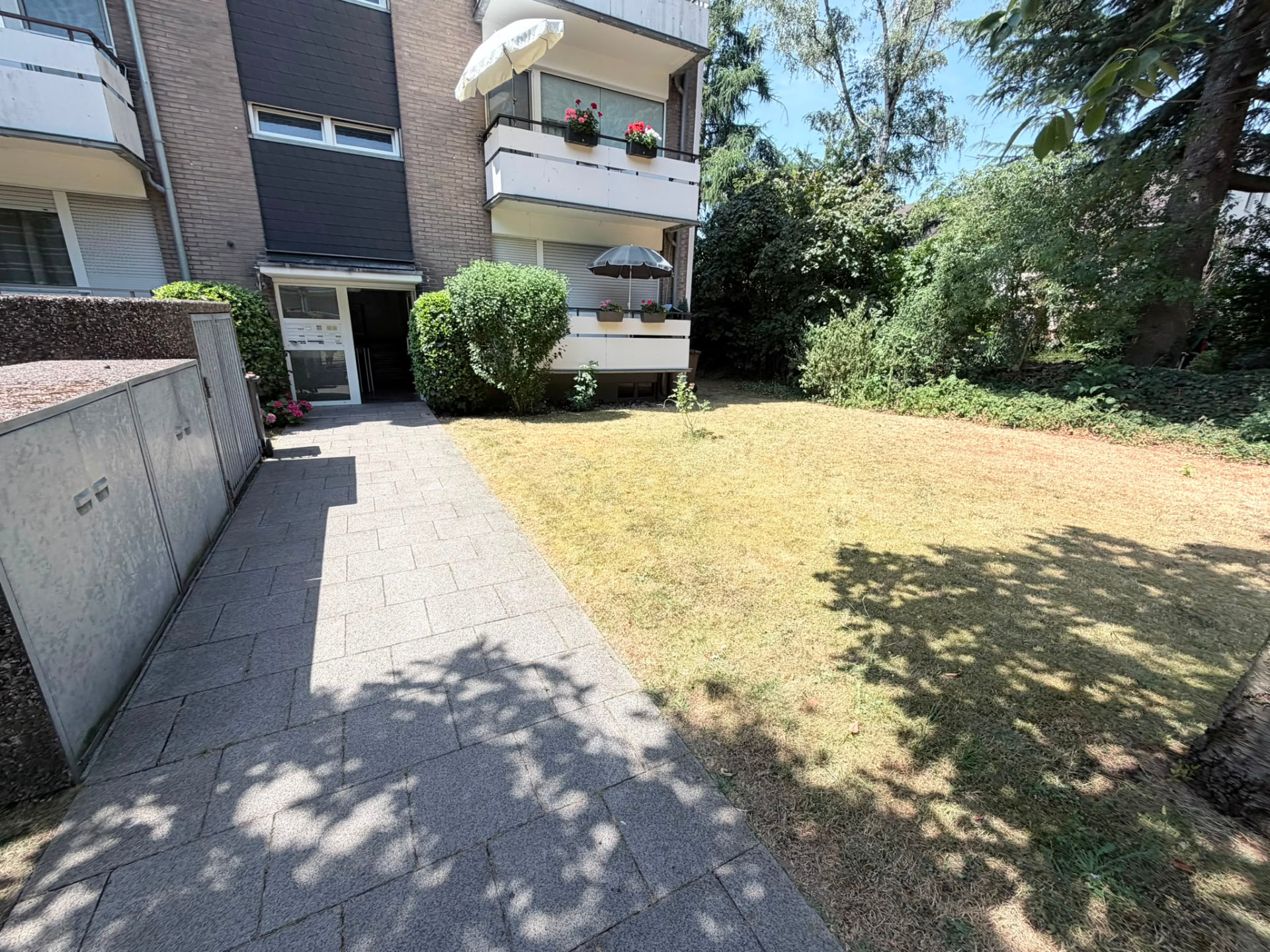Gepflegte Außenanlage mit Rasenfläche und Zuwegung an einem Mehrfamilienhaus