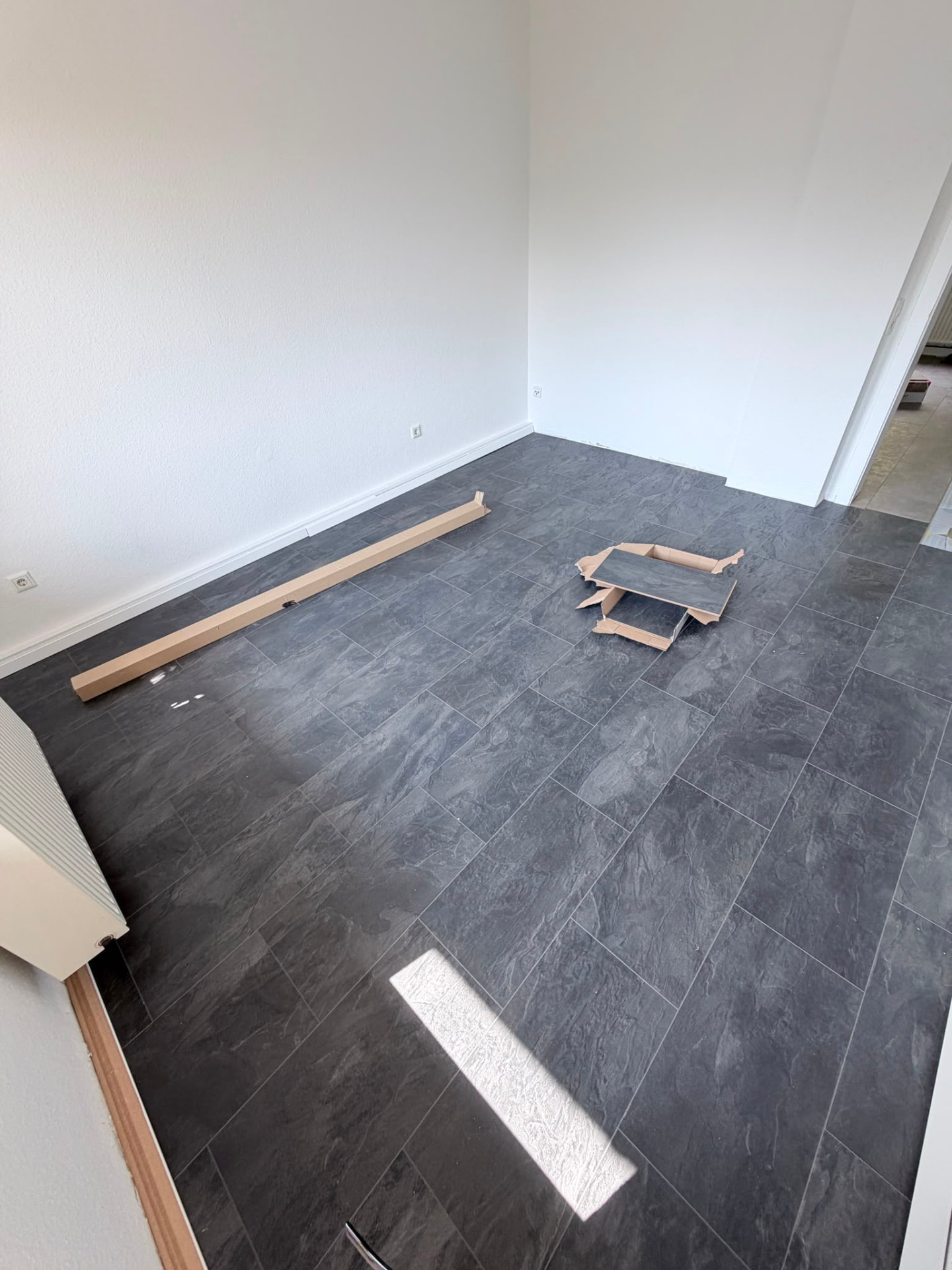Frisch verlegter dunkler Fliesenboden in einer Wohnung durch IE immocare